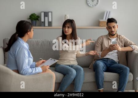 Eine genörte arabische Frau beschwerte sich während einer psychologischen Konsultation über die Smartphone-sucht ihres Mannes Stockfoto