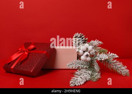 Offene rote Geschenkbox mit winterlicher festlicher Dekoration auf rotem Hintergrund. Weihnachtspodium für Kosmetik- und Kosmetikprodukte. Stand mit Neujahrsdekor Stockfoto