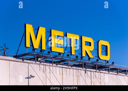 MonCalieri, Turin, Italien - 6. Dezember 2021: Metro-Logo auf dem Gebäude eines Supermarkts am blauen Himmel. Metro Cash and Carry ist ein international führendes Spiel Stockfoto