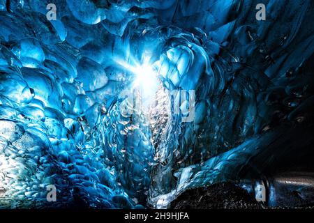 Blaues Gletschereis mit Loch in den Himmel mit Sonneneinbruch, aus einer Eishöhle im Gletscher. Breioarmerkurjokull, Teil des Vatnajokull Gletschers Stockfoto