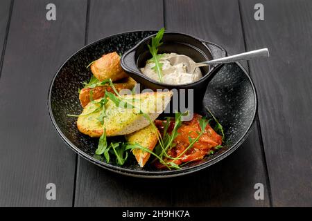 Knusprig geröstetes Knoblauchbrot mit saurem Quark und geschmorter Tomate Stockfoto