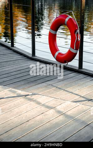 Vertikale Aufnahme einer roten Rettungsboje, die an den Schienen eines Piers hängt Stockfoto