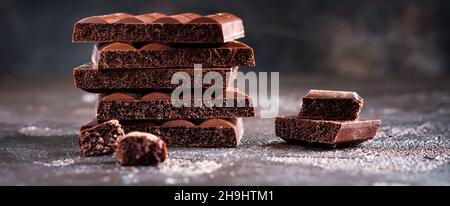 Stapel von bitter poröser luftiger Schokolade auf dunklem altem Hintergrund. Selektiver Fokus. Stockfoto