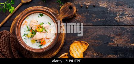 Warme finnische cremige Suppe mit Lachs und Gemüse in alter Keramikschale auf altem Holzhintergrund. Rustikaler Stil. Draufsicht. Stockfoto