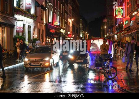 Blick auf die Frith Street, mit Ronnie Scott's Jazz Club und Bar Italia, und ein Fahrradtuktuk wartet auf eine Fahrt. Aus einer Serie von Fotos, die bei einer regnerischen Nacht in Soho, London, aufgenommen wurden. Fotodatum: Donnerstag, 27. Juli 2017. Bildnachweis sollte lauten: Richard Gray/EMPICS Entertainment Stockfoto