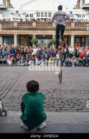 Ein Kind beobachtet einen Eskapologen-Einradfahrer, der in Covent Garden in London für Menschenmengen auftrat. Aus einer Reihe von Bildern von Straßenkünstlern in London, Großbritannien. Fotodatum: Donnerstag, 3. August 2017. Bildnachweis sollte lauten: Richard Gray/EMPICS Entertainment Stockfoto