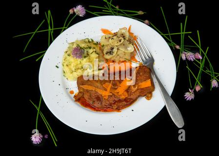 Rinderfilet mit Karottensauce, Topinabur und Kartoffelpüree auf schwarzem Hintergrund mit Schnittlauch, Nahaufnahme. Stockfoto