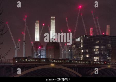 Ein Zug auf der Chelsea-Brücke und im Hintergrund rote Warnleuchten auf Kranen rund um das derzeit sanierte Battersea Power Station in London. Fototermin: Dienstag, 2. Januar 2018. Bildnachweis sollte lauten: Richard Gray/EMPICS Entertainment Stockfoto