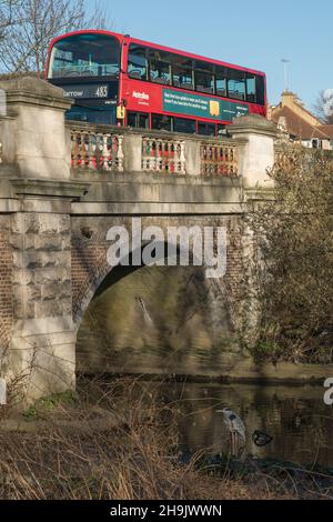 Ein Kran (Vogel) auf dem Fluss Brent fährt als roter Bus über eine Brücke in der Nähe von Hanwell im Westen Londons. Fotodatum: Sonntag, 25. Februar 2018. Bildnachweis sollte lauten: Richard Gray/EMPICS Entertainment Stockfoto