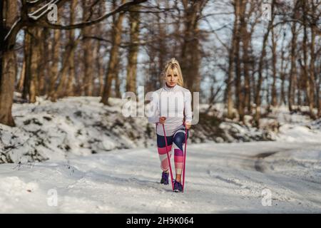 Sportlerin macht Ausfallschritte mit Power-Gummi, während sie an verschneiten Wintertagen in der Natur steht. Gesundes Leben, Winterfitness, Outdoor-Fitness Stockfoto