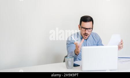 Wütender unangenehmer Geschäftsmann, der an der Rezeption sitzt und über eine Online-Videokonferenz spricht und unangenehme Diskussionen über Meinungsdecis führt Stockfoto