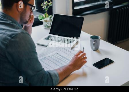 Ernsthafte nachdenklich nachdenklich konzentriert Junge casual Kaufmann oder Unternehmer im Amt ausfüllen Steuererklärung papers Dokumente für IRS Stockfoto