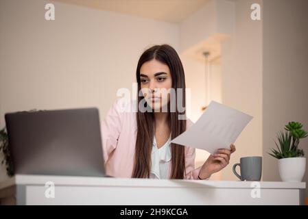 Serious nachdenklich nachdenklich konzentriert junge Erwachsene casual businesswoman Buchhalter Buchhalter zu Hause oder im Büro beim Betrachtern und Arbeiten mit Lapt Stockfoto