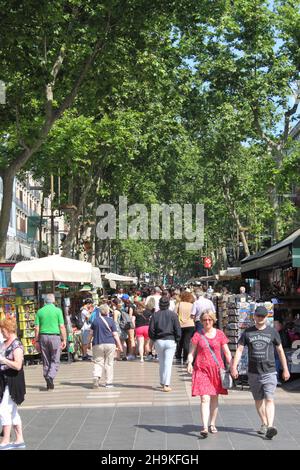 Barcelona, Spanien - 17. Mai 2021: Menschenmenge zu Fuß auf der von Bäumen gesäumten La Rambla. Die beliebte Touristenfußgängerzone Las Ramblas Stockfoto