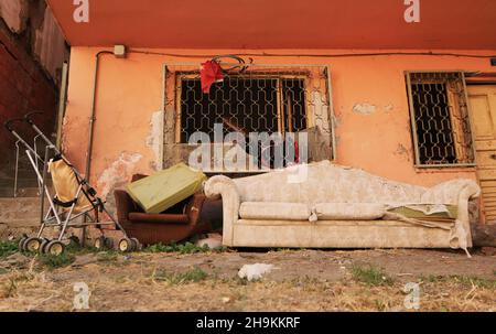 Heruntergekommenes Haus, veraltetes Sofa und Sessel, alter Kinderwagen, rosa bemalte Wand. Stockfoto