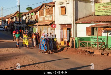 Ihosy, Madagaskar - 05. Mai 2019: Eine Gruppe von unbekannten madagassischen Frauen und Männern in hellen Kleidern, die auf der Stadtstraße spazieren, die Nachmittagssonne scheint ihnen. Typi Stockfoto