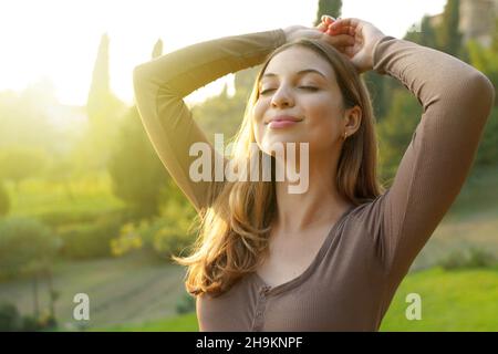 Porträt einer freien Frau, die saubere Luft in der Natur atmet. Glückliches Mädchen mit erhobenen Armen in Glückseligkeit. Entspannung, Ruhe im Freien, Wellness gesunder Lebensstil Co Stockfoto