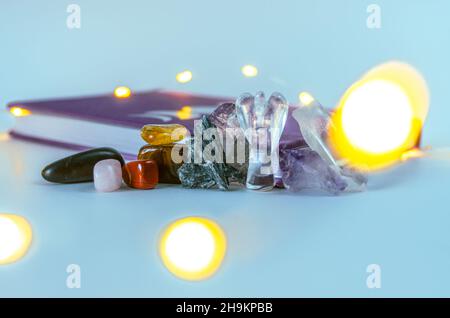 Nahaufnahme von Engelskristall aus klarem Quarz in der Nähe eines Mondjournals mit Weihnachtslichtern und Weihrauch auf dem Hintergrund. Konzept: Spirituelle Selbstversorger-Praktiken Stockfoto