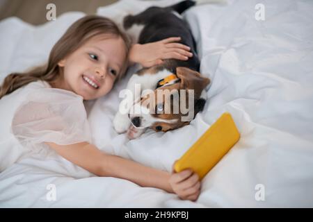 Hübsches kleines Mädchen, das Selfies mit ihrem lustigen vierbeinigen Freund macht Stockfoto