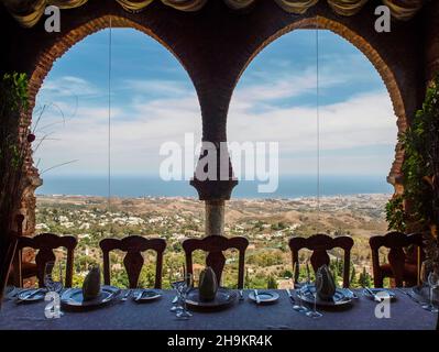 Panoramablick von der Sierra de Mijas auf das Meer von einem großen Fenster mit zwei Bögen eines Restaurants ohne Kunden. Stockfoto