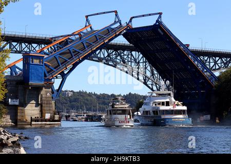 Zwei Boote, die an einer geöffneten Fremont Bridge in Seattle, Washington, vorbeifahren. Stockfoto