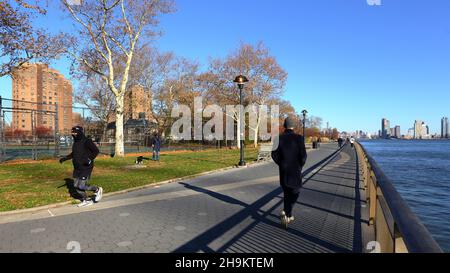 Jogger und Menschen auf der East River Waterfront Esplanade im East River Park in der Lower East Side von Manhattan, New York, NY. 23. November 2021. Stockfoto