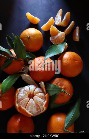 Frische Mandarinen mit grünem Blatt isoliert auf dunklem Hintergrund. Direkt darüber. Stockfoto