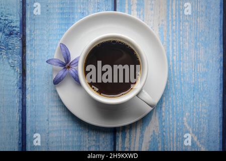Kaffee. Weiße Tasse Kaffee auf einem blauen Holztisch. Stockfoto