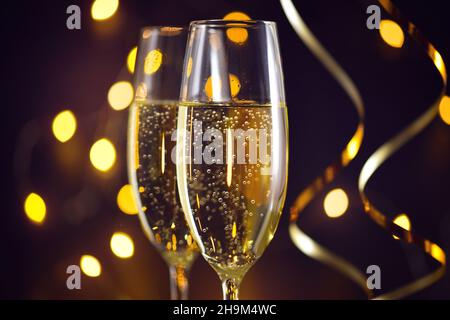 Zwei Sektgläser auf dunklem Hintergrund mit Weihnachtsbeleuchtung Stockfoto