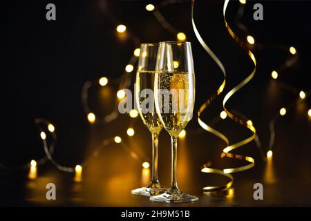 Zwei Sektgläser auf dunklem Hintergrund mit Weihnachtsbeleuchtung Stockfoto