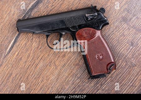 Draufsicht auf eine Pistole des makarov-Systems auf einem Holzhintergrund. Die Hauptwaffe der russischen Polizei. Stockfoto