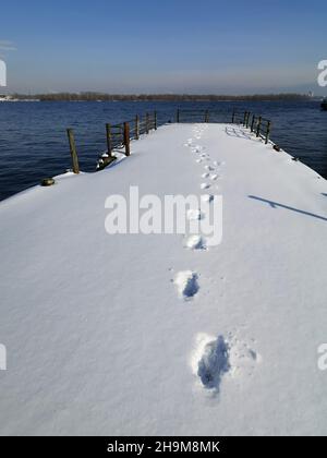 Menschliche Fußabdrücke auf weißem, sauberem Schnee. Ausgetretener Pfad entlang der schneebedeckten Pier am Fluss. Spuren von Fußabdrücken. Wintersaison. Winterspaziergang in den s Stockfoto