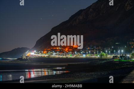 Llanfairfechan Beach und Penmaenmawr Mountain mit der A55 Expressway Road dazwischen. Bild aufgenommen im November 2021. Stockfoto