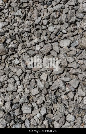 Die Textur von feinem Kies. Granitgrauer Hintergrund. Viele kleine Steine liegen auf dem Boden. Stockfoto