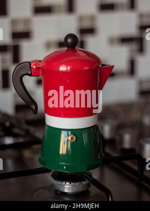 Bunte Espressomaschine mit Herdplatten, Moka-Topf, auf dem Herd mit brennendem Feuer Stockfoto