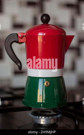 Farbenfrohe Espressomaschine mit Herdplatten, Mokakanne auf dem Herd mit brennendem Feuer Stockfoto