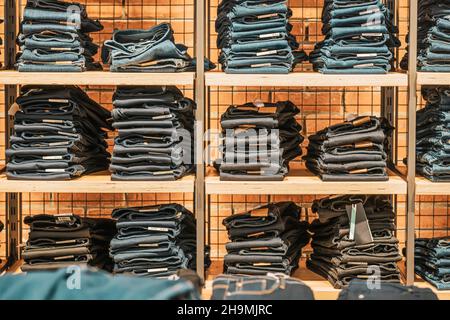 Gefaltete Jeans auf Holzregalen, Bekleidungsgeschäft, modernes Einkaufszentrum. Freizeit-Bekleidung für Jugendliche Stockfoto