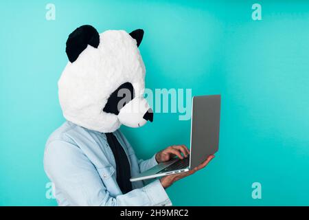 Glücklicher Mann in Panda-Maske mit einem Laptop Stockfoto