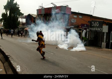 Lagos, Nigeria, 7th. Dezember 2021. Passanten laufen vor Polizeitrengas am Gymnasium, Ojodu, Lagos, Nigeria, weg, wo ein Lieferwagen, der angeblich von Verkehrsbeamten gejagt wurde, einige Schüler tötete, die von der Schule zurückkehrten. Während der Augenzeuge sagte, dass mindestens 17 Schüler starben, bestätigte die Polizei am Dienstag, dass drei Tote, 12 Verletzte, bei dem Unfall starben. Foto von Adekunle Ajayi Stockfoto