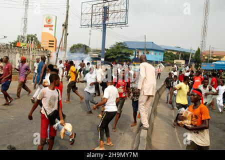 Lagos, Nigeria, 7th. Dezember 2021. Demonstranten fliehen vor Polizeitrengas am Gymnasium in Ojodu, Lagos, Nigeria, wo ein Lieferwagen, der angeblich von Verkehrsbeamten verfolgt wurde, einige Studenten tötete, die von der Schule zurückkehrten. Während der Augenzeuge sagte, dass mindestens 17 Schüler starben, bestätigte die Polizei am Dienstag, dass drei Tote, 12 Verletzte, bei dem Unfall starben. Foto von Adekunle Ajayi Stockfoto