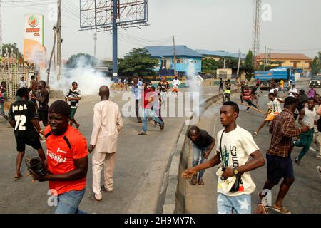 Lagos, Nigeria, 7th. Dezember 2021. Demonstranten fliehen vor Polizeitrengas am Gymnasium in Ojodu, Lagos, Nigeria, wo ein Lieferwagen, der angeblich von Verkehrsbeamten verfolgt wurde, einige Studenten tötete, die von der Schule zurückkehrten. Während der Augenzeuge sagte, dass mindestens 17 Schüler starben, bestätigte die Polizei am Dienstag, dass drei Tote, 12 Verletzte, bei dem Unfall starben. Foto von Adekunle Ajayi Stockfoto