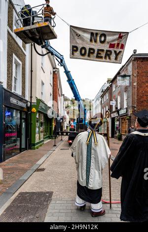 Mitglieder der Cliffe Bonfire Society in religiösem Kostüm Uhr als traditionelle Zeichen und Banner werden in den Straßen, Lewe, Sussex, Großbritannien, aufgesetzt. Stockfoto