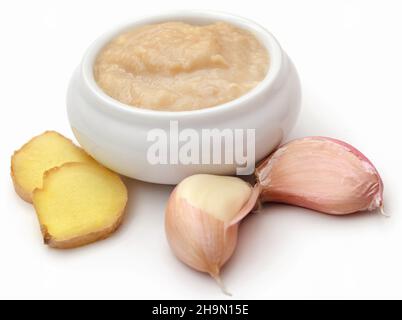 Ingwer und Knoblauch mit Paste auf weißem Hintergrund Stockfoto