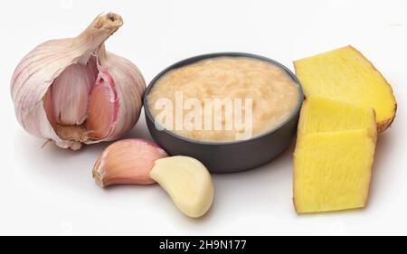 Ingwer und Knoblauch mit Paste auf weißem Hintergrund Stockfoto