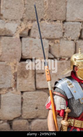 Soldat, der das Pilum hält, Speer der alten römischen Armee. Hintergrund der Granitwand mit Quadersteinen Stockfoto