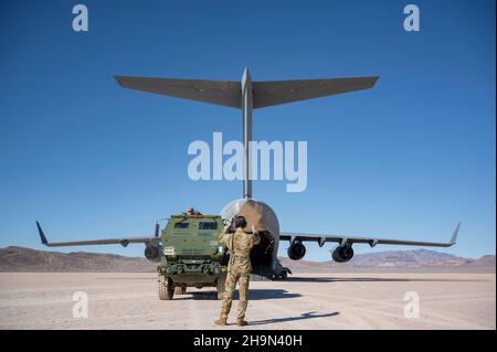 Ein Ladermeister der US-Luftwaffe aus dem 6th Airlift Squadron, Joint Base McGuire-Dix-Lakehurst, N.J., lädt ein M142 High Mobility Artillery Rocket System (HIMARS), das dem 3rd Bataillon, 321st Field Artillery Regiment, Fort Bragg, North Carolina, während der Integration der U.S. Air Force Weapons School auf dem Nellis Air Force Base, Nevada, zugewiesen wurde. 4. Dezember 2021. Loadmasters sind für das Verladen, die Sicherung, die ordnungsgemäße Gewichtsverteilung und die Sicherheit der Passagiere vor und während des Flugbetriebs verantwortlich. (USA Luftwaffe Foto von Airman 1st Klasse Zachary Rufus) Stockfoto