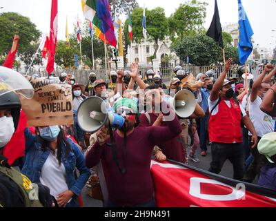 Ein Mann mit einem Megaphon konfrontiert die Polizei, als Hunderte von Anhängern von Präsident Pedro Castillo und der Partei Peru Libre auf die Straße gingen, um gegen den Antrag auf Amtsenthebung des Präsidenten zu protestieren, der nur 4 Monate nach seinem Amtsantritt im Kongress vorgelegt wurde. Castillo wird unter anderem des Einflusses bei Beförderungen der Streitkräfte und heimlichen Treffen außerhalb des Präsidialhauptquartiers beschuldigt. Stockfoto