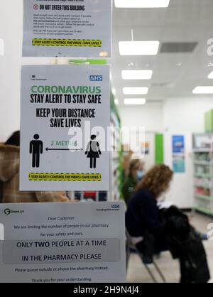 London, Großbritannien. 7th Dez 2021. Hinweise mit Maßnahmen zur epidemischen Prävention und Bekämpfung sind an der Tür einer Apotheke in London, Großbritannien, am 7. Dezember 2021 zu sehen. In Großbritannien wurden weitere 101 Fälle der Omicron COVID-Variante gemeldet, was die Gesamtzahl auf 437 beläuft, bestätigten die britischen Gesundheitsbehörden am Dienstag. Kredit: Li Ying/Xinhua/Alamy Live Nachrichten Stockfoto