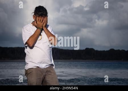 Junger Hippie-Weißer, der sein Gesicht mit den Händen versteckt. Konzept der psychischen Probleme. Stockfoto