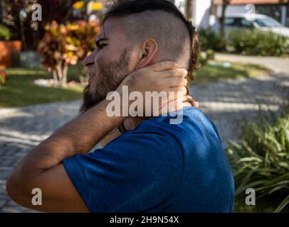Mann im jungen Alter und Hipster-Look und blaues Hemd mit Schmerzen im Hals. Stockfoto